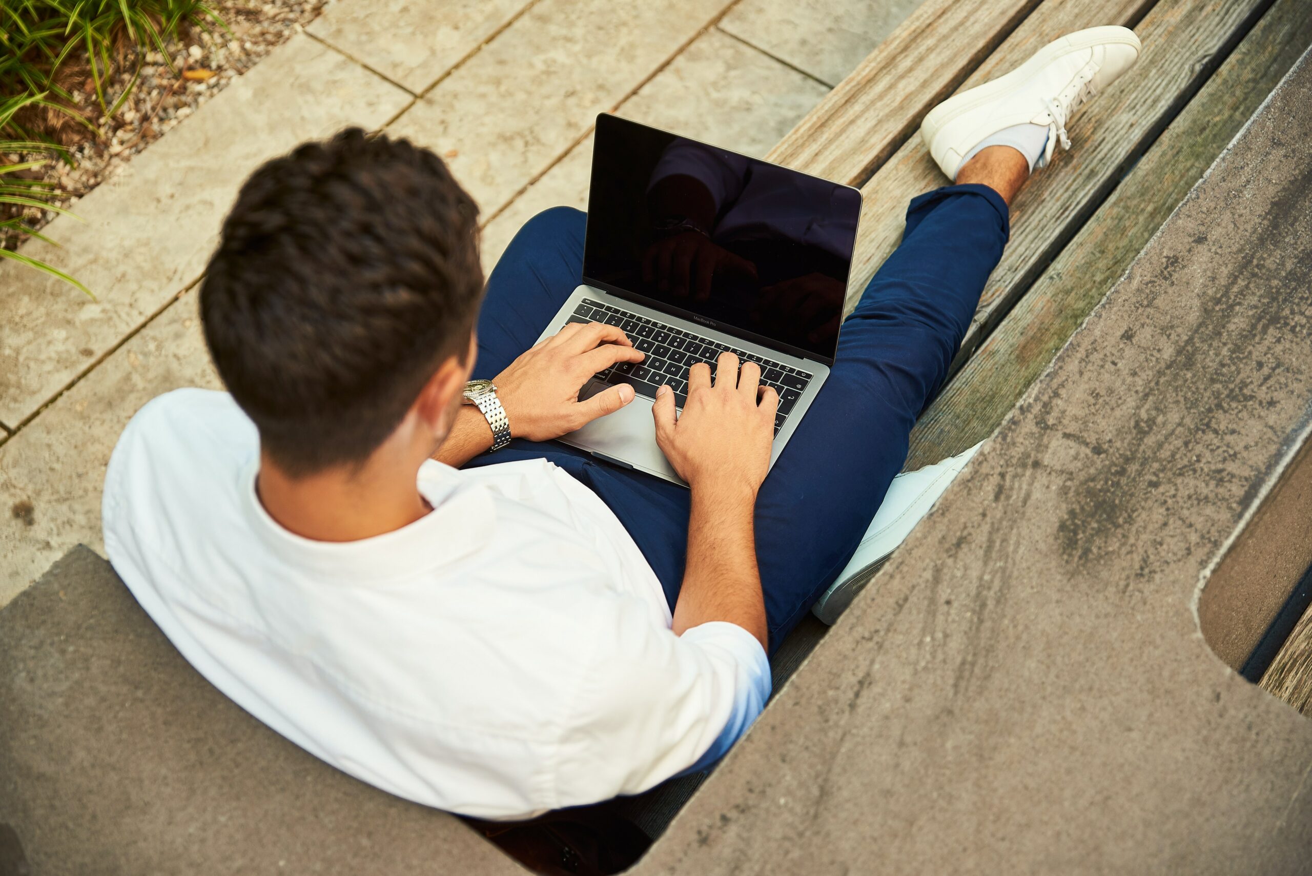 man sitting on bench in manchester working on laptop