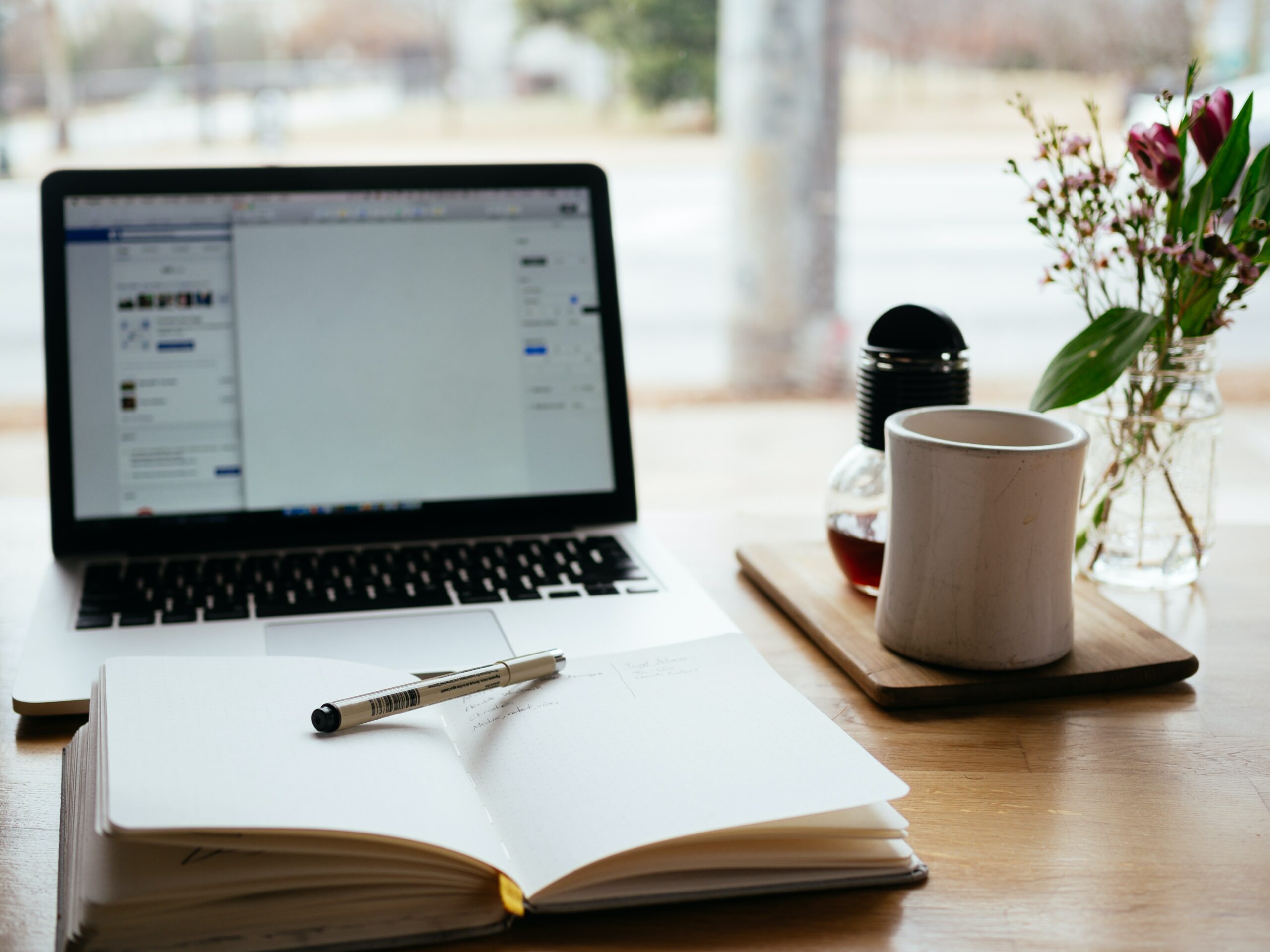 desk with laptop, coffee and notebook